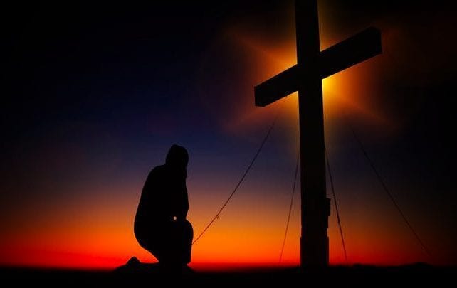 man kneeling cross